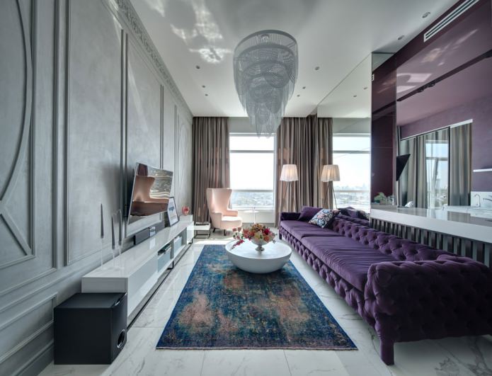 интерьер гостиной с фиолетовым диваном и красивой люстрой