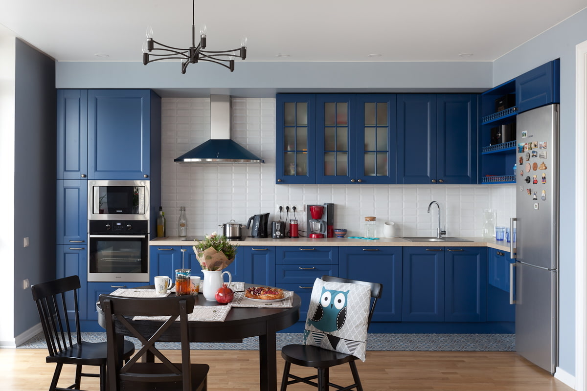 Кухня гостиная с синим диваном и белой кухней